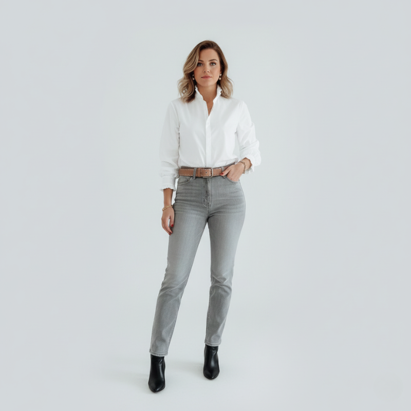 Woman wearing a white shirt and gray jeans on a plain background