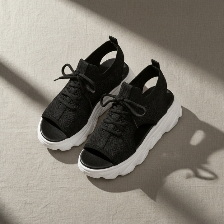 Black sandals with white soles on a beige surface