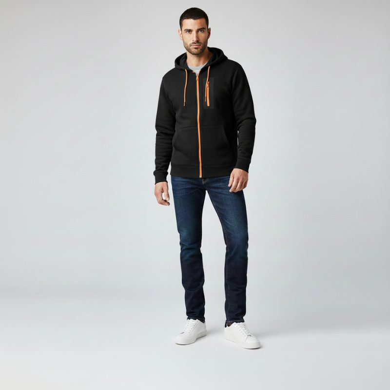 Man wearing a black hoodie with an orange zipper, blue jeans, and white sneakers on a light gray background