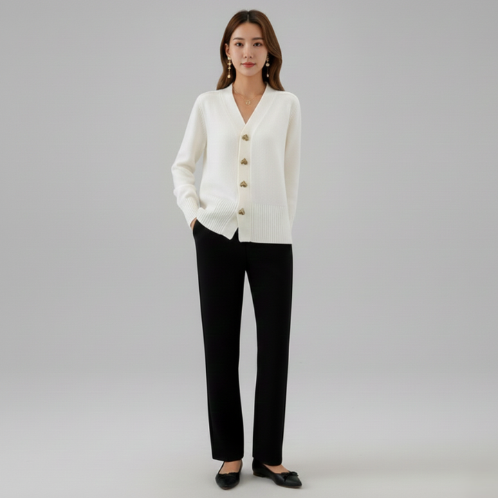 Woman wearing a white cardigan and black pants on a gray background