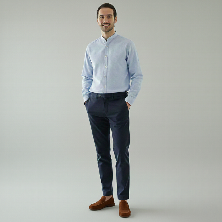 Man wearing a light blue shirt and dark pants on a gray background