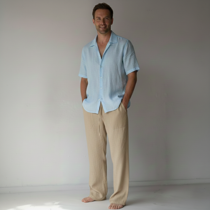 Man wearing a light blue shirt and beige pants against a plain background