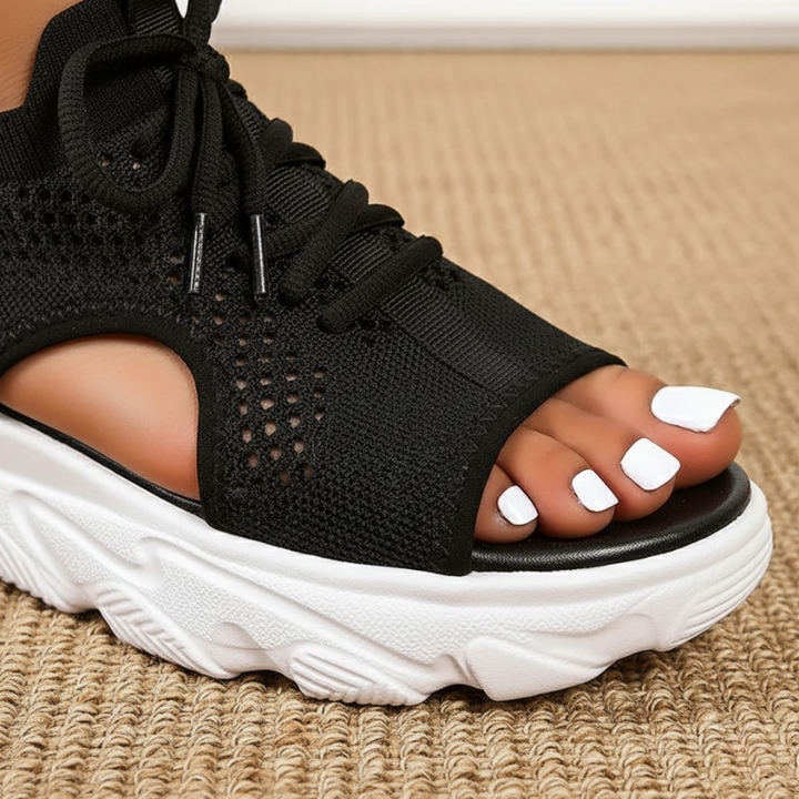 Black open-toe sandal with white sole on a textured surface