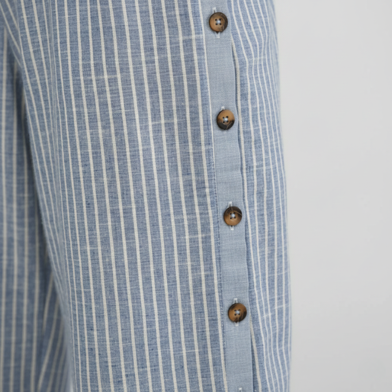 Close-up of a blue and white striped shirt with wooden buttons on a light gray background