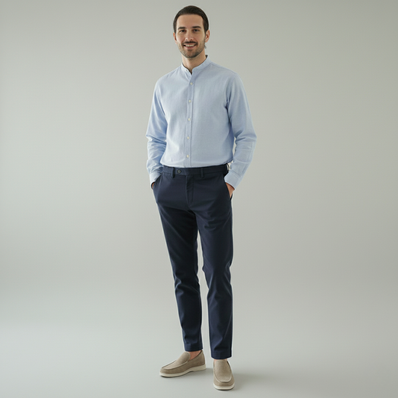 Man wearing a light blue shirt and dark blue pants on a plain background