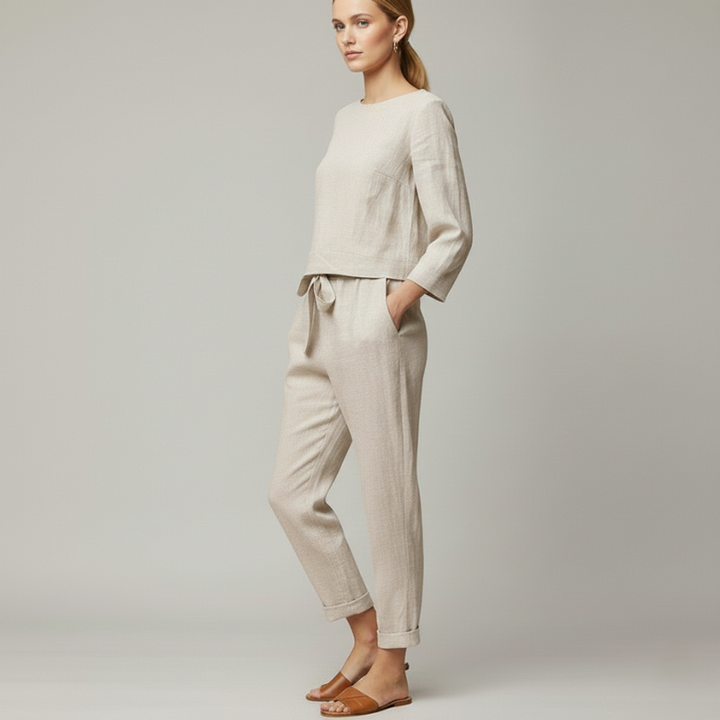 Woman wearing a beige long-sleeve lounge top and matching jogger pants in a clean studio environment.