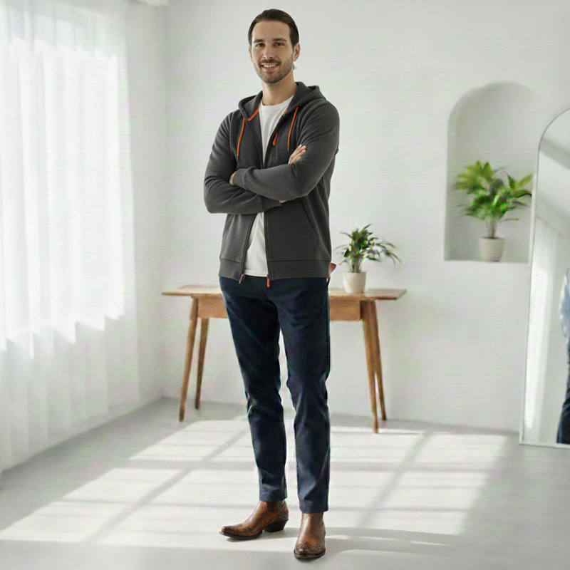 Man standing in a bright room with white walls and a wooden desk.