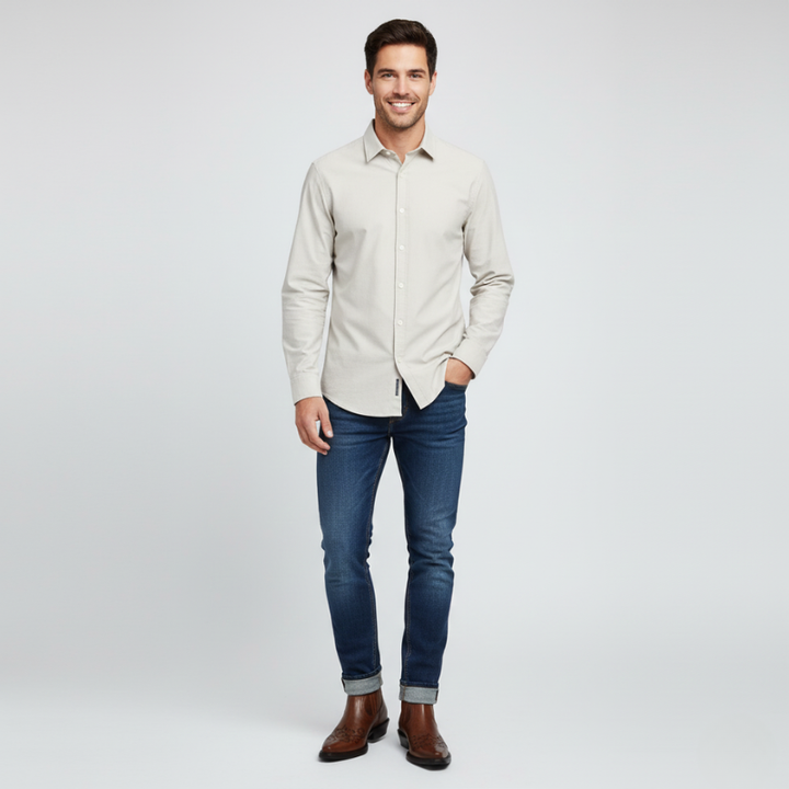 Man wearing a beige shirt and blue jeans on a white background