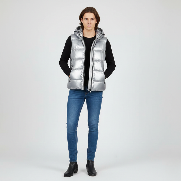 Person wearing a silver puffer vest over a black shirt with blue jeans on a white background
