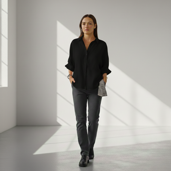 Woman wearing a black shirt and gray pants in a bright room with sunlight filtering through.