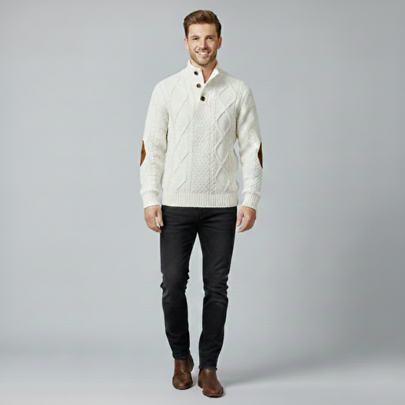 Man wearing a cream sweater and dark pants on a gray background