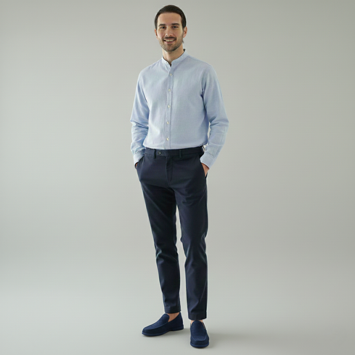 Man wearing a light blue shirt and dark blue pants on a gray background