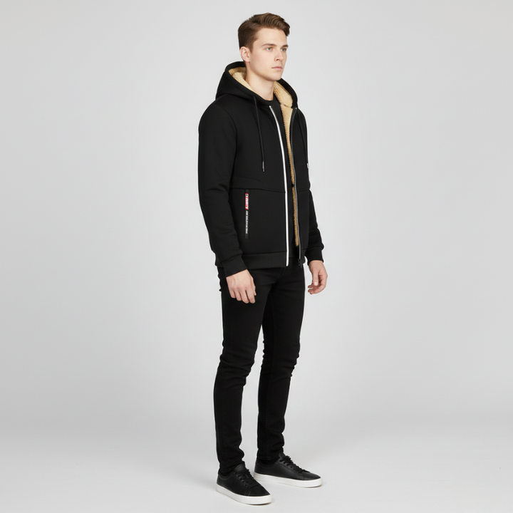 Side view of a man wearing a black sherpa lined hoodie with black pants and black sneakers.