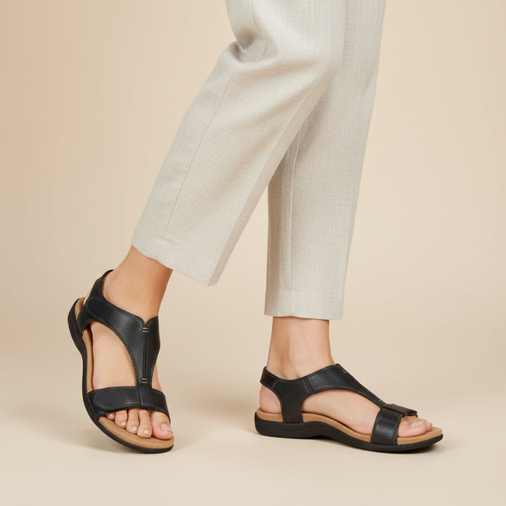 Close-up of black leather strappy sandals showing stitching, footbed design, and textured sole.