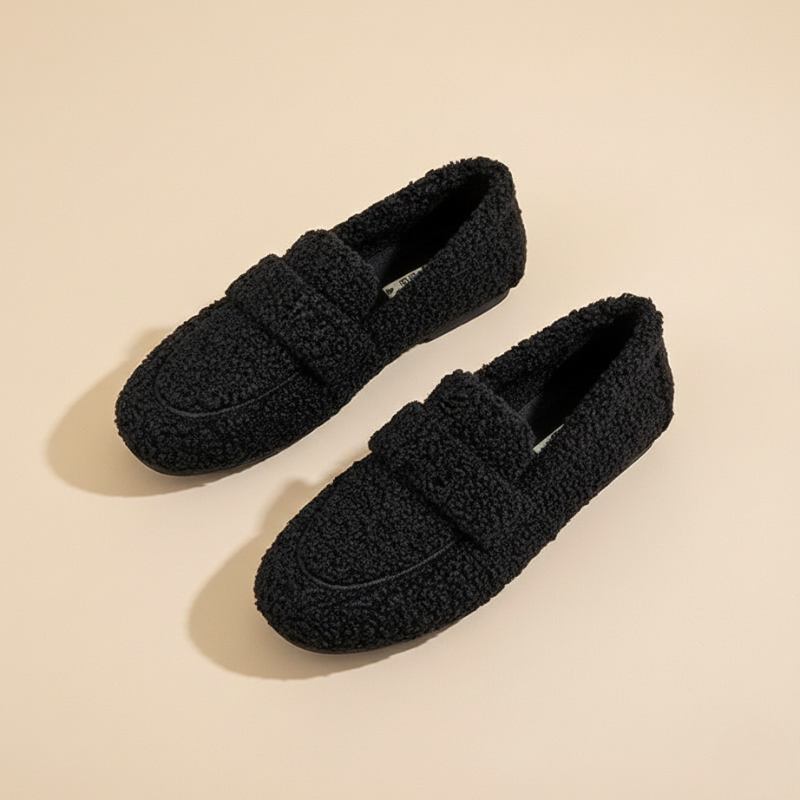 Pair of black loafers on a beige background