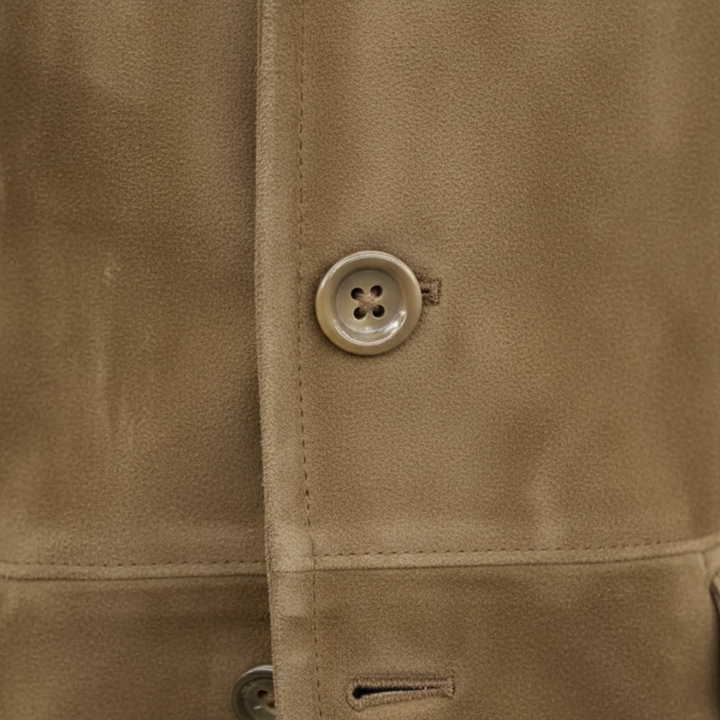 Close-up of a brown blazer showing button stitching, textured fabric, and lapel structure.