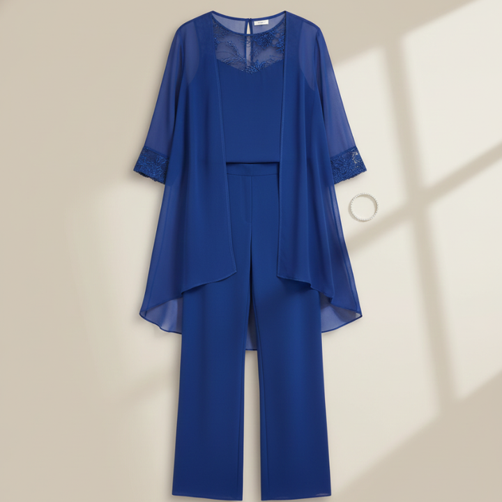 Royal blue chiffon pant set hanging on a hanger showing lace neckline and tiered top design.