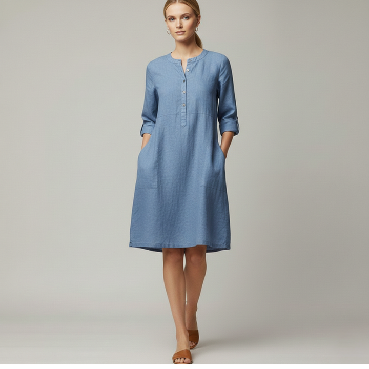 Close-up of a blue dress showing textured fabric, front buttons, and clean stitching detail.