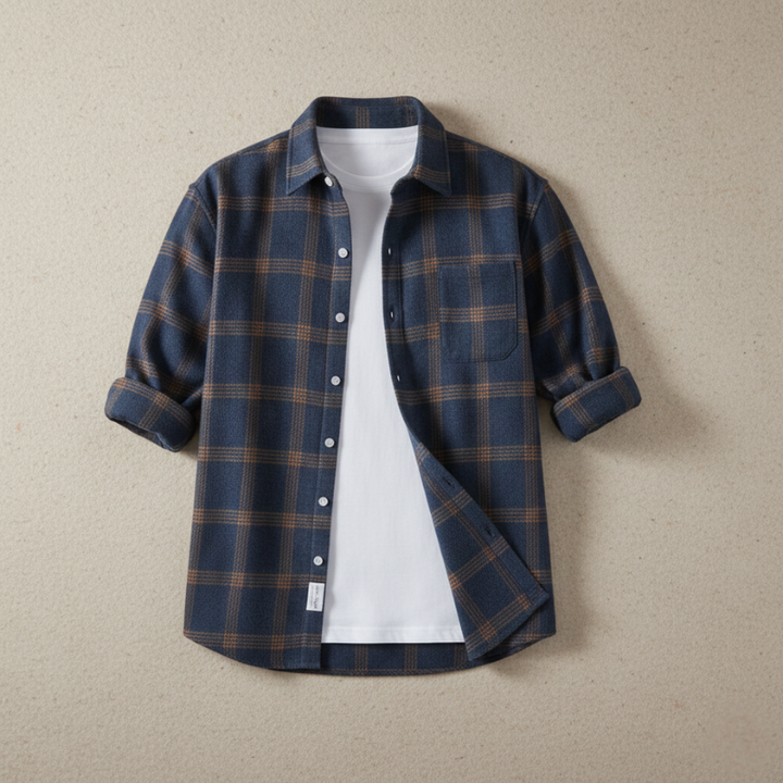 Flatlay of a blue plaid flannel shirt displayed on a neutral background showing pattern, collar shape, and fabric texture.
