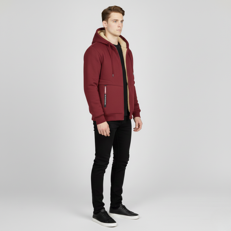 Side view of a man wearing a burgundy sherpa lined hoodie with black pants and black sneakers.