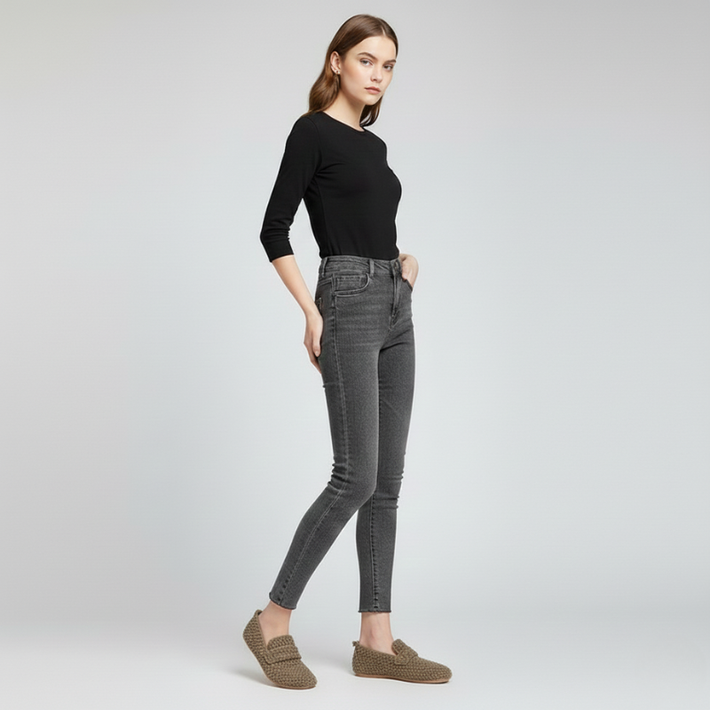 Woman wearing gray jeans and a black top on a white background