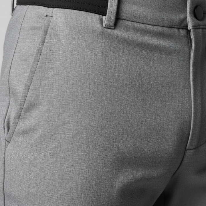 Close-up of gray pants with a belt and button detail on a light gray background