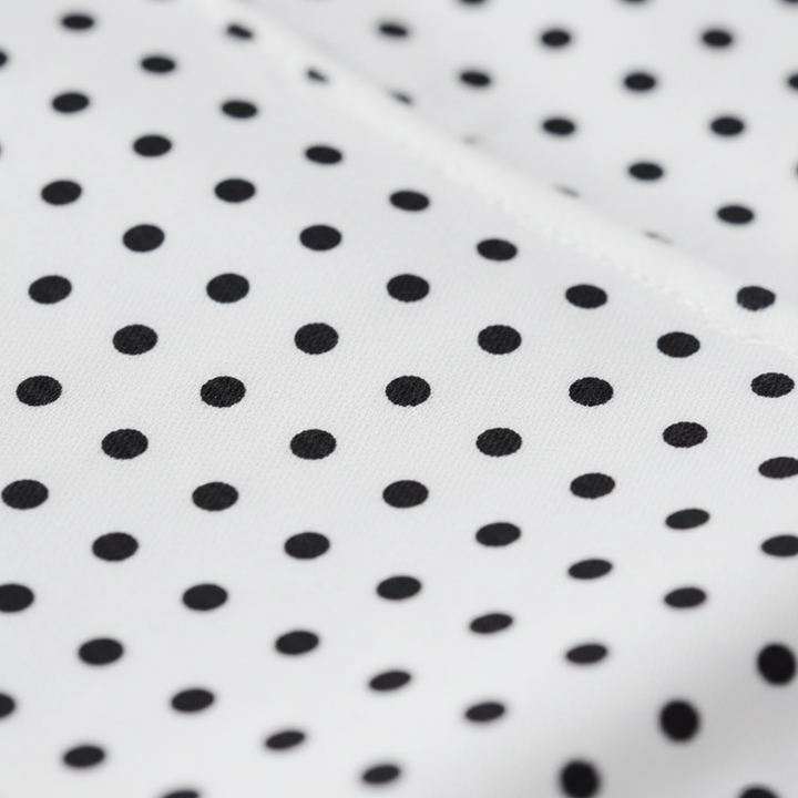 Close-up of black polka dots on a white fabric background