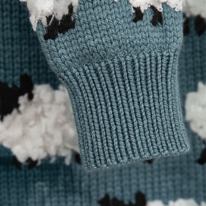 Close-up of the cloud-pattern knit sweater showing soft textured stitches and white cloud shapes.