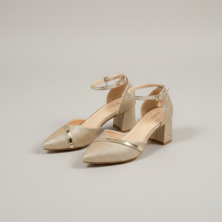 Pair of gold glittery high-heeled shoes on a light gray background