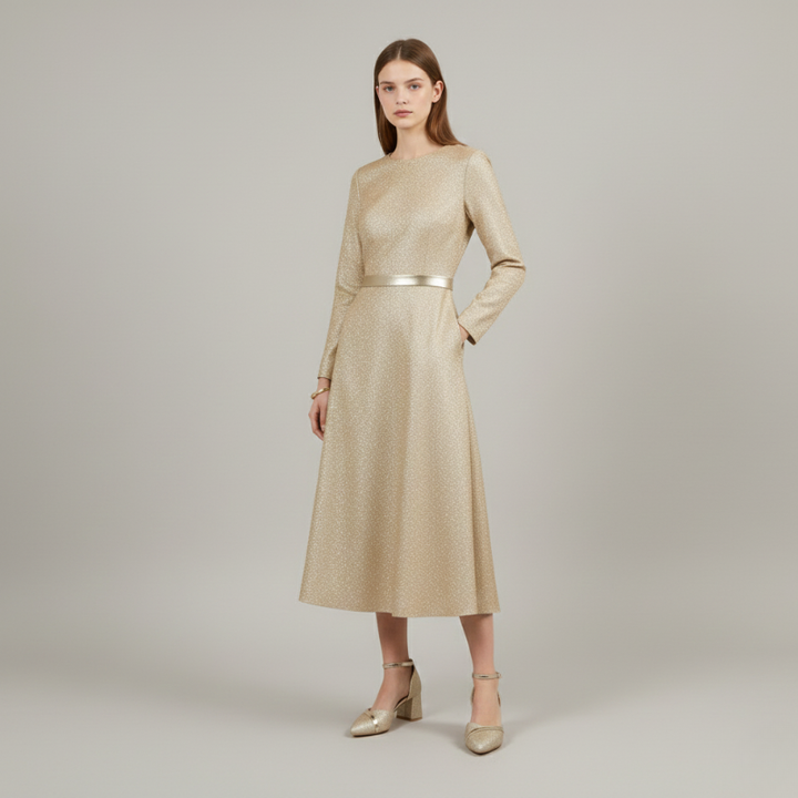 Woman wearing a gold long sleeve midi dress with a fitted waist, styled with gold block heel ankle strap shoes on a neutral studio background.