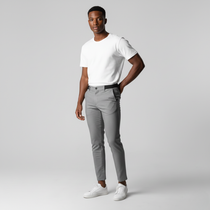 Man wearing a white t-shirt and gray pants on a light gray background