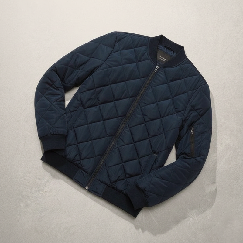 Navyblaue Steppjacke flach ausgelegt auf hellem Untergrund, mit sichtbarer Steppstruktur und Reißverschlussdetail.