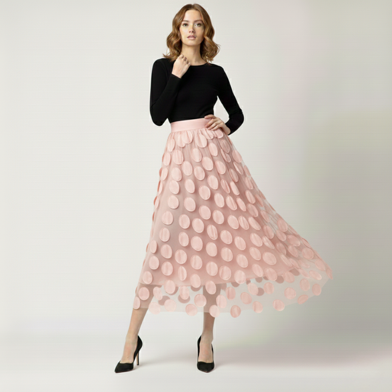 Woman wearing a black top and pink polka dot skirt on a white background