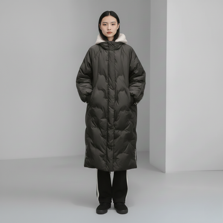 Person wearing a long dark green puffer coat against a plain background