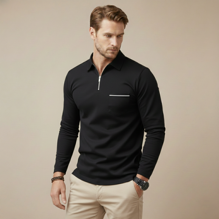 Man wearing a black long-sleeve zip polo shirt with a minimal modern look in soft room lighting.