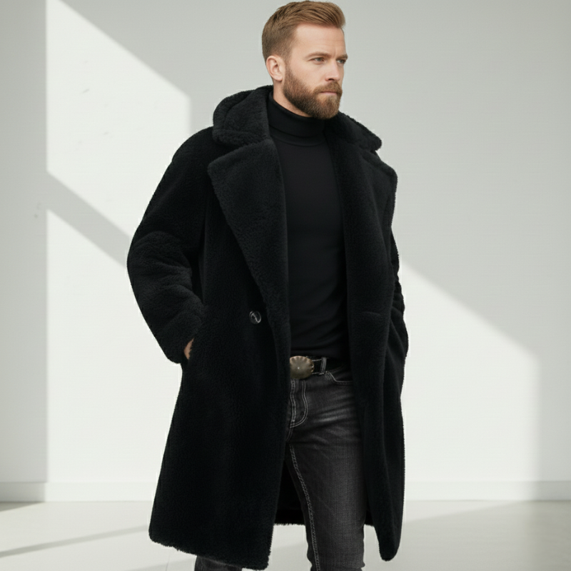 Man wearing a long black wool coat with structured shoulders and high collar in studio lighting.