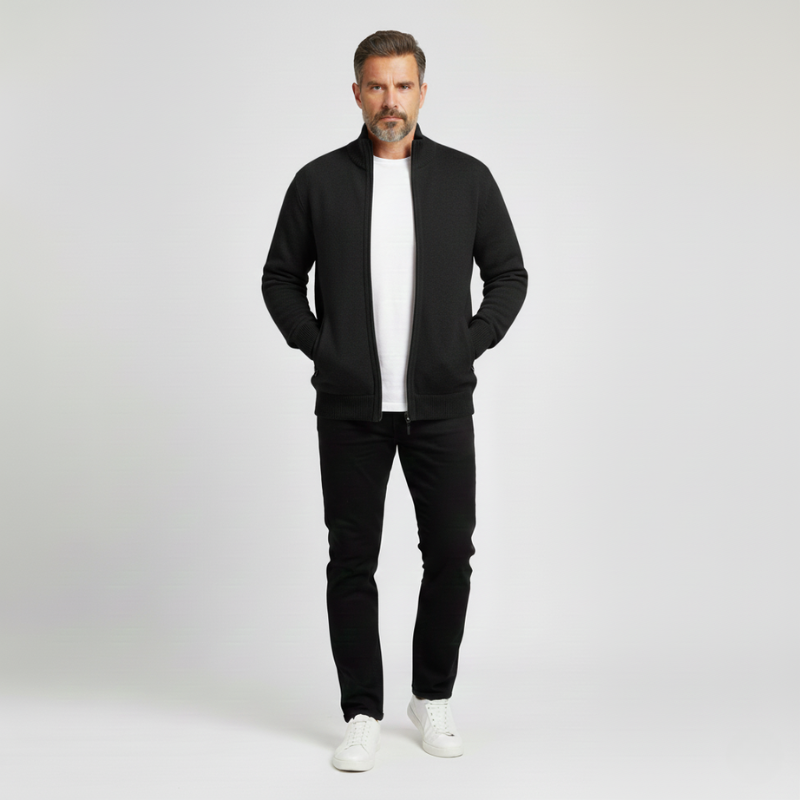 Man wearing a black jacket, white shirt, black pants, and white shoes on a light gray background