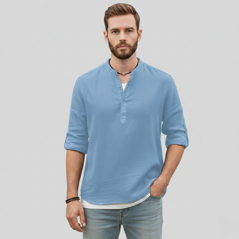 Man wearing a light blue linen shirt paired with white pants in natural indoor lighting.