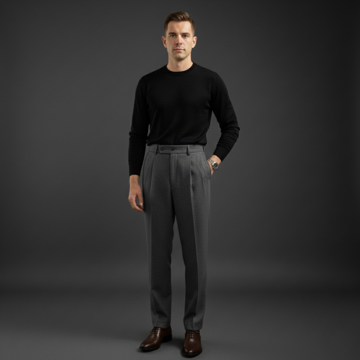 Man wearing charcoal tailored dress pants paired with a black sweater in a dark studio setting.