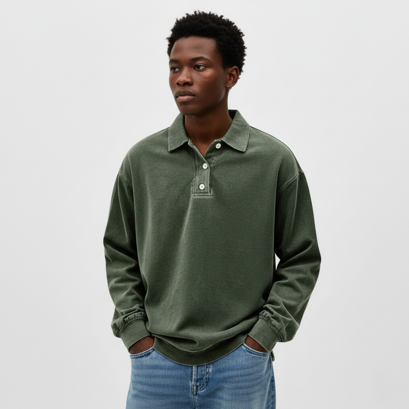 Man standing indoors wearing a green knit polo sweatshirt styled casually in natural room light.