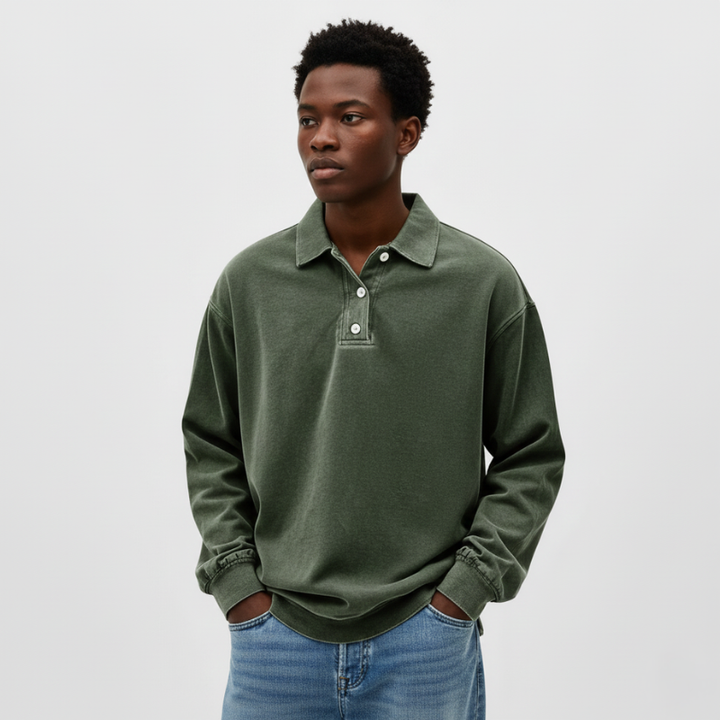 Man standing indoors wearing a green knit polo sweatshirt styled casually in natural room light.