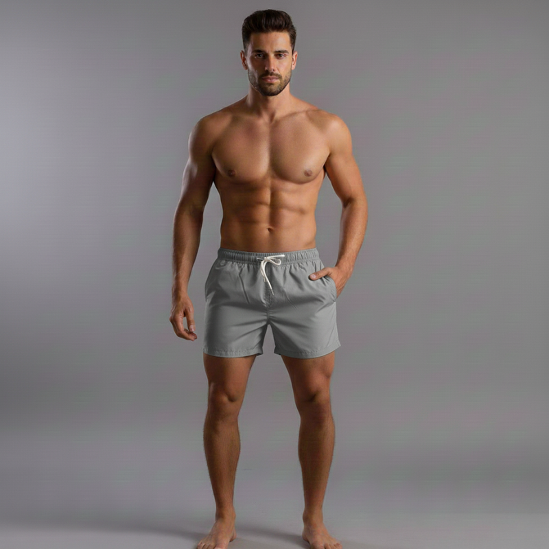 Man wearing gray swim shorts against a plain background