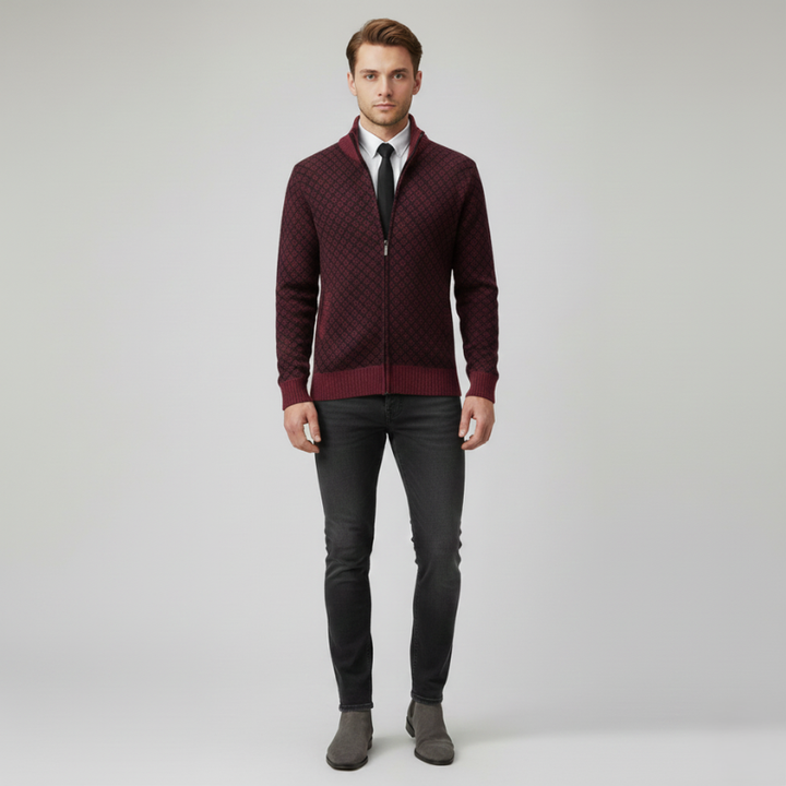 Full-body image of a man wearing a maroon zip-up cardigan over a dress shirt and tie in a studio setting.