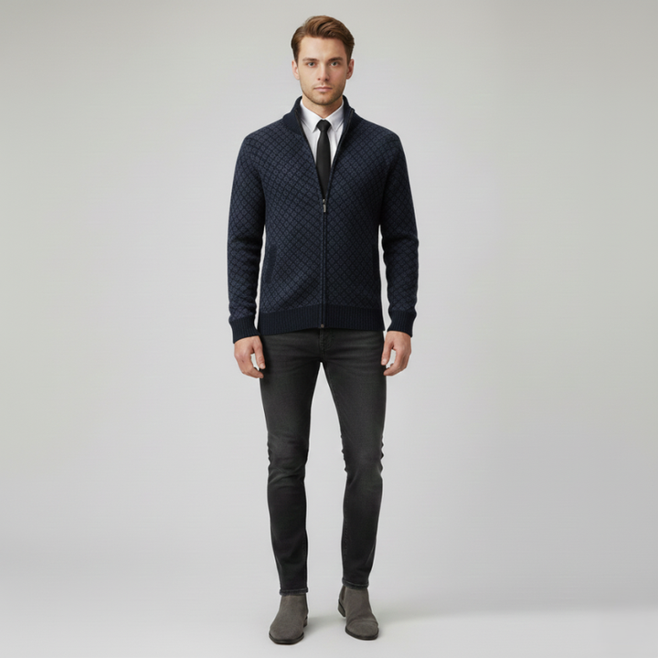 Man standing in a navy blue patterned zip-up cardigan styled with dress pants and a collared shirt.