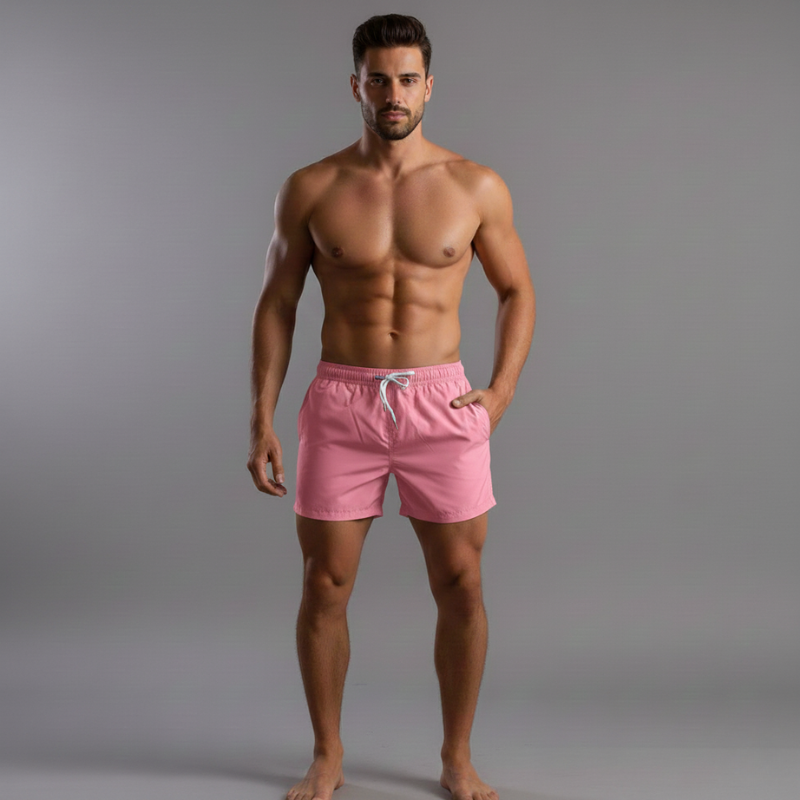 Man wearing pink swim shorts against a gray background