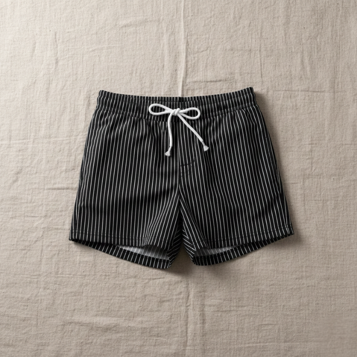 Black and white striped shorts with a drawstring on a beige fabric background