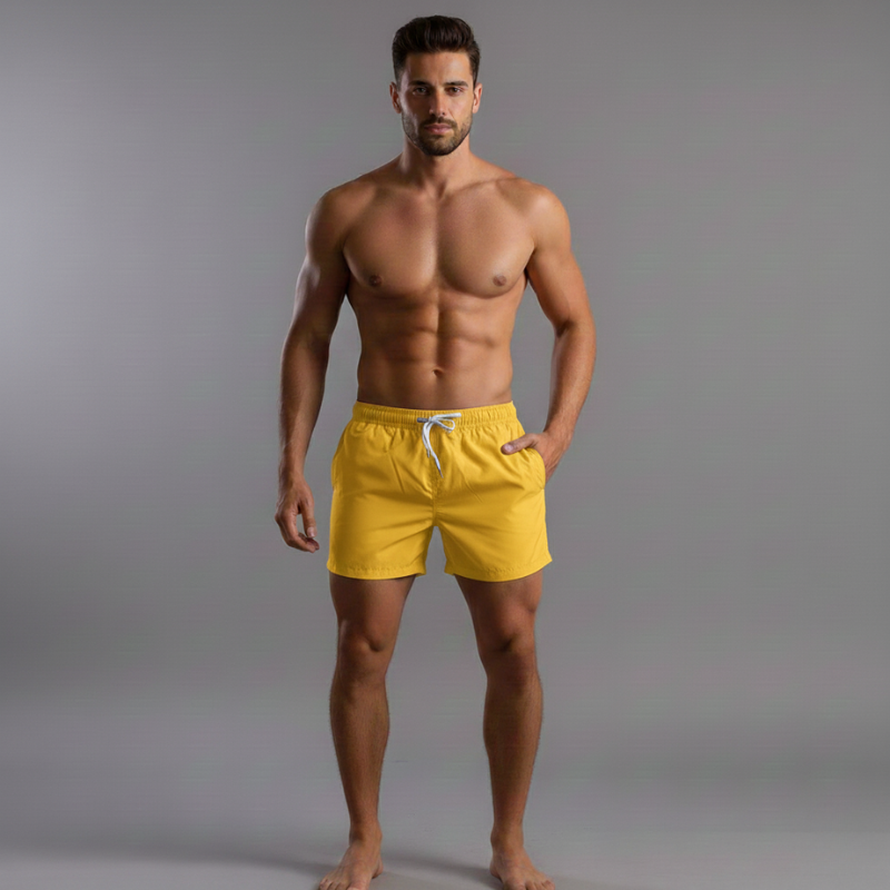 Man wearing yellow swim shorts against a gray background