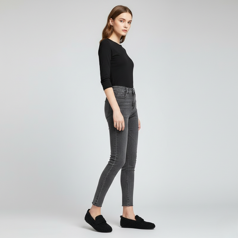 Woman wearing gray jeans and a black top on a light gray background