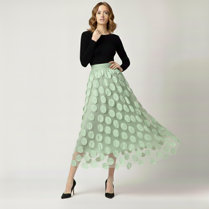 Woman wearing a black top and light green skirt with a polka dot pattern on a white background