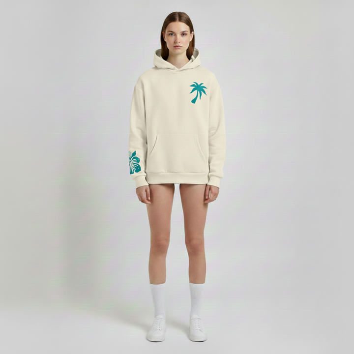 Person wearing a beige hoodie with palm tree designs on a plain background